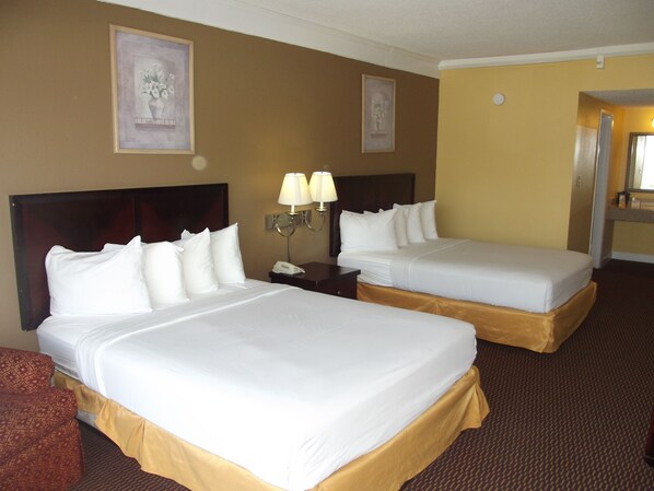 A hotel room with two beds, a nightstand with a phone, wall-mounted lamps, and framed artwork.