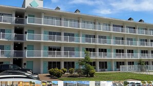 A multi-story hotel with balconies, a parking area, and a small garden.