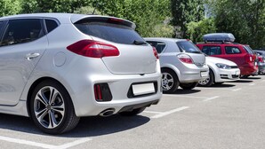 A parking lot with several cars, including a white SUV and a red SUV.