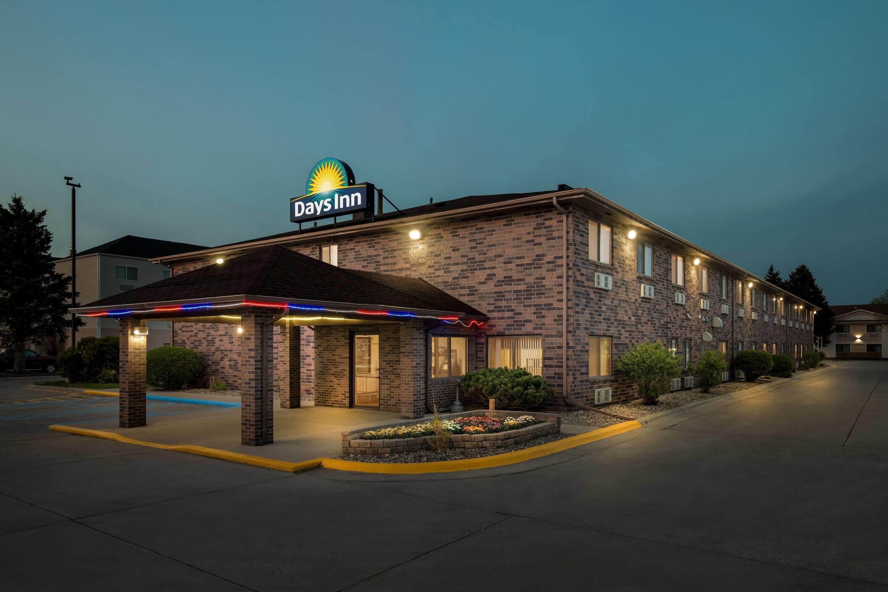 A Days Inn with a brick facade, a covered entrance, and a landscaped garden area.