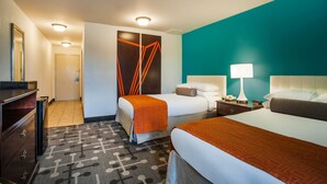 Een hotelkamer met twee bedden, een bureau, een dressoir en een badkamers deur.