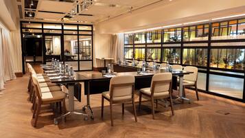 A conference room with a long table, chairs, and a view through large windows.