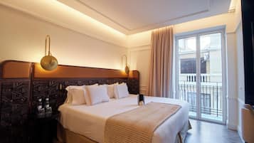 A hotel room with a large bed, a nightstand, a lamp, and a view of the outside balcony.