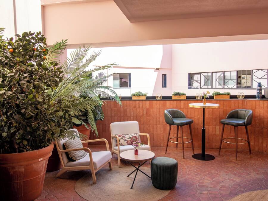 Un área de estar al aire libre con una mesa, sillas y una planta en maceta.