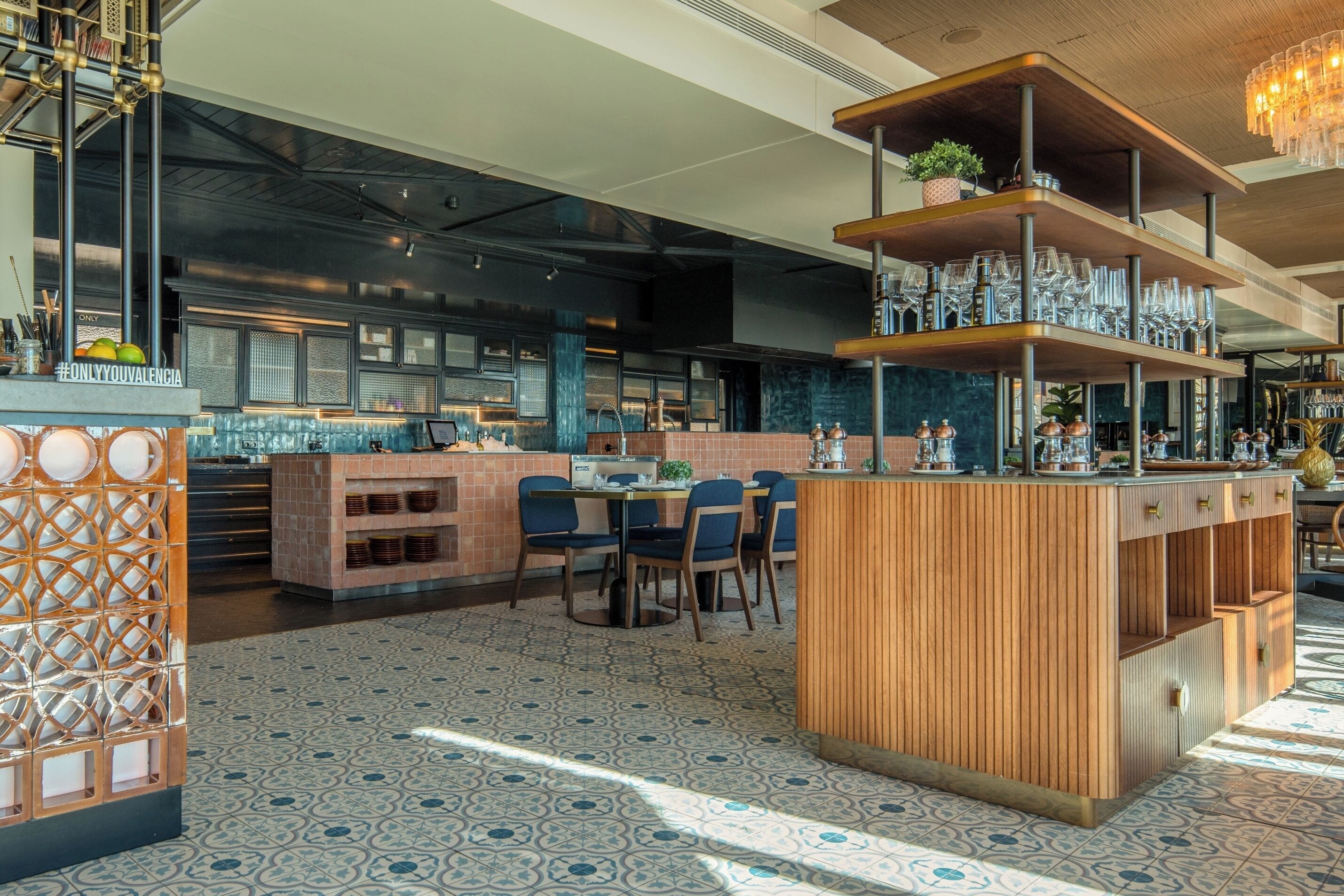 Una zona de bar moderna con mostrador de madera, asientos y una estantería decorativa de vidrio.