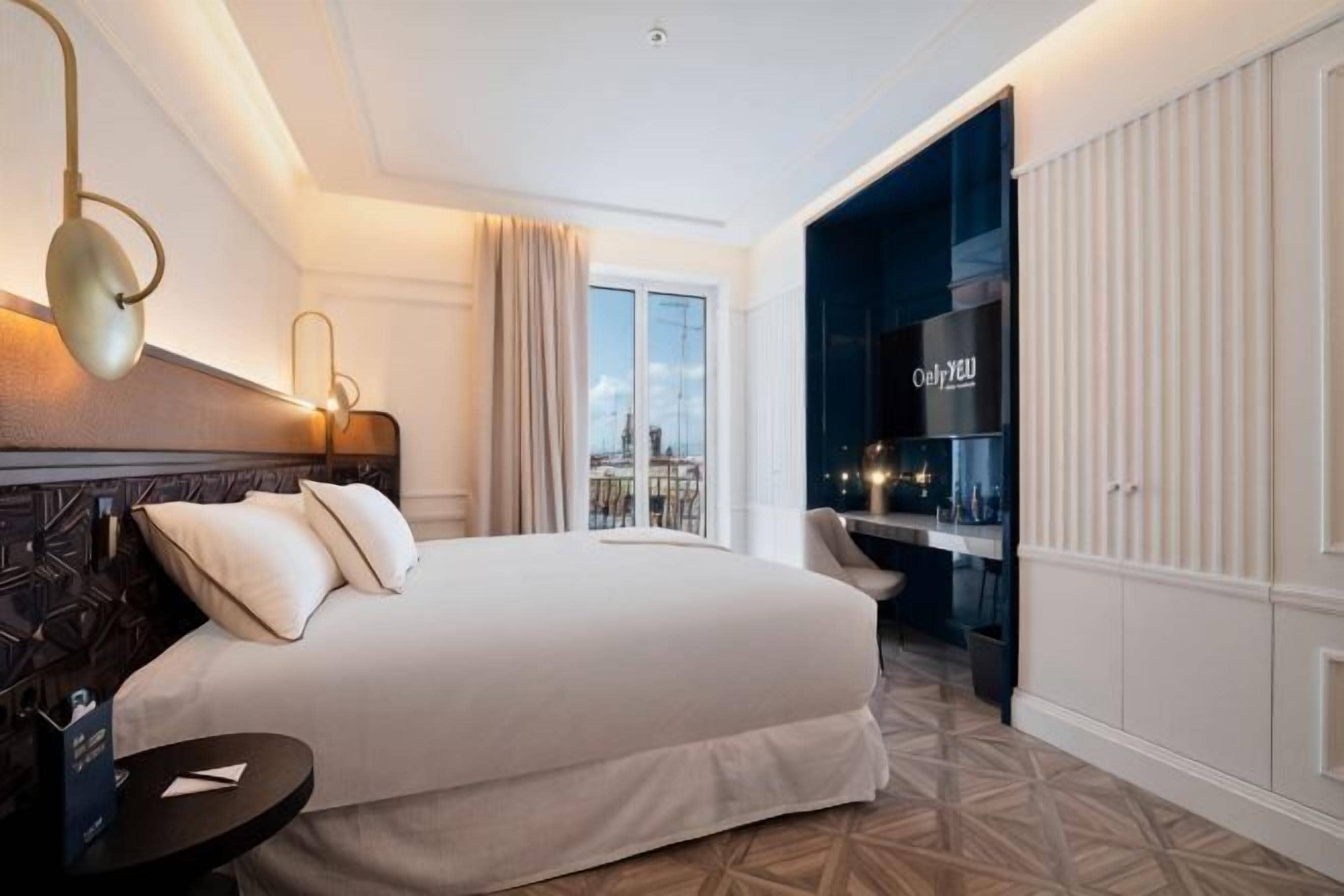 Habitación de hotel con una cama grande, un escritorio, una silla, vistas a la ciudad y un minibar.