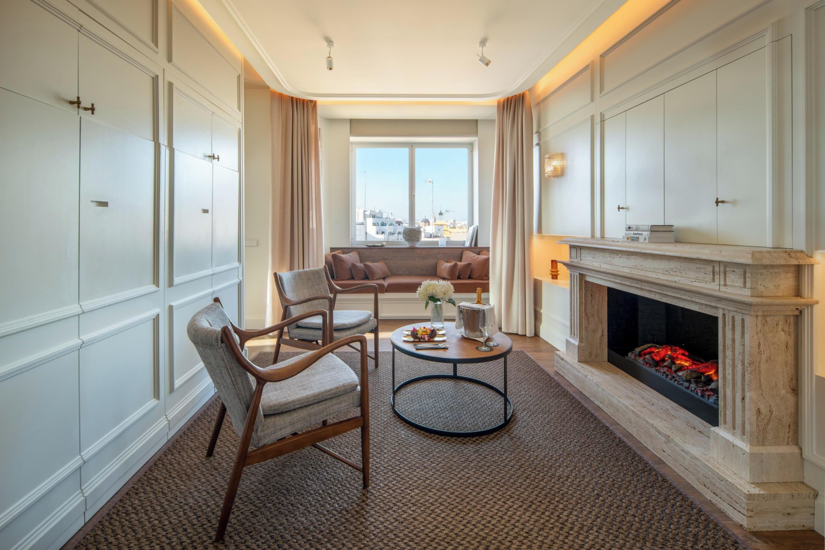 Habitación de hotel con chimenea, zona de estar y vistas a la ciudad.