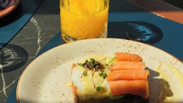 Un plato con comida, un vaso de jugo de naranja y un tenedor sobre una mesa.