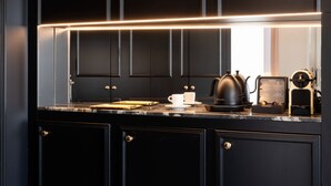 Una cocina moderna con armarios negros, encimera de mármol, cafetera y hervidor.