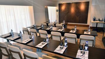 A conference room with multiple tables and chairs, equipped with water bottles and nameplates.