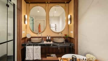 Un baño moderno con tocador de doble lavabo, dos espejos y un mueble de madera con un recipiente para artículos de tocador.