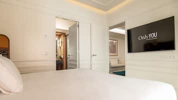 A hotel room with a large bed, a TV on the wall, and a door leading to a bathroom.