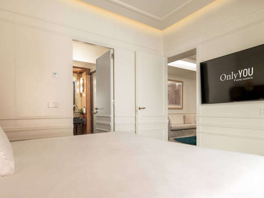 Een hotelkamer met een groot bed, een televisie aan de muur en een deur naar een badkamer.
