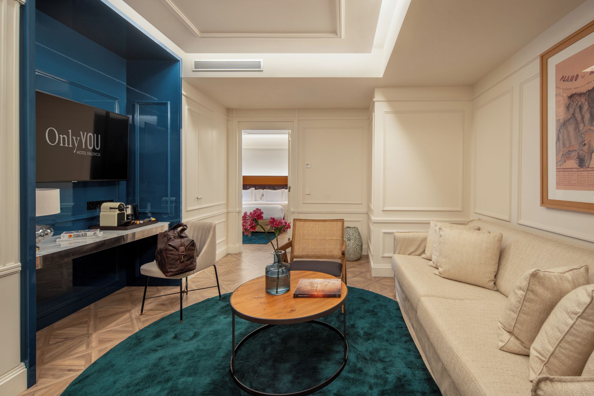 Habitació d'hotel moderna amb televisió, escriptori, cadira, sofà i una finestra gran.