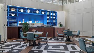 A modern bar area with blue shelving, a variety of glassware, and seating arrangements.