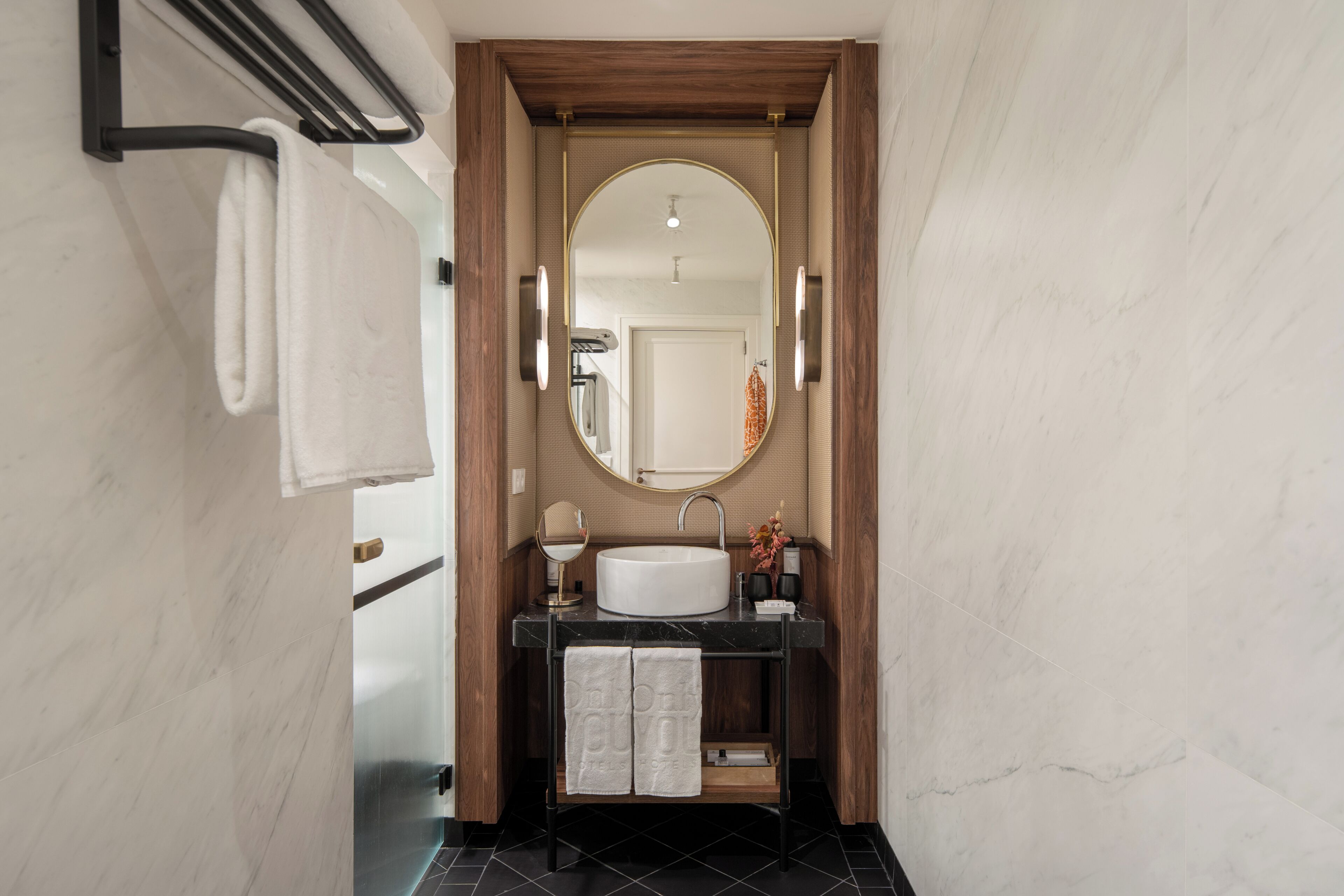 Un baño moderno con lavamanos de mármol, tocador de madera y un espejo grande.