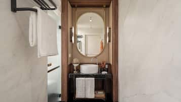 Un baño moderno con lavamanos de mármol, tocador de madera y un espejo grande.