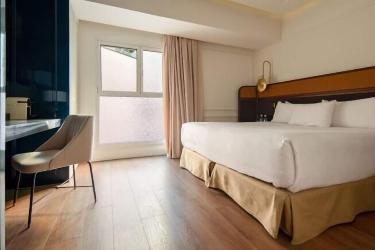 A hotel room with a bed, a desk, and a chair.