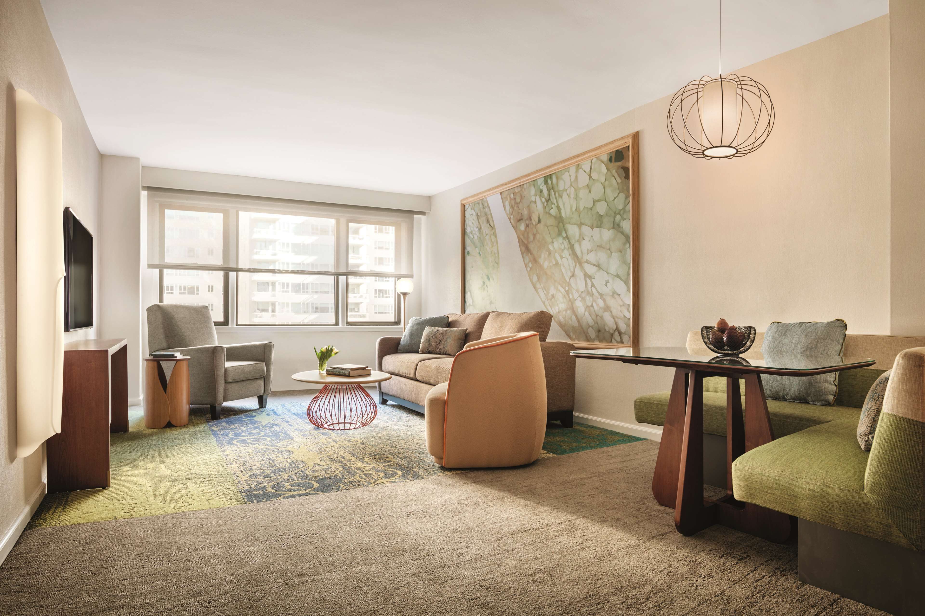 A modern living room with a sofa, armchairs, a coffee table, and a TV.