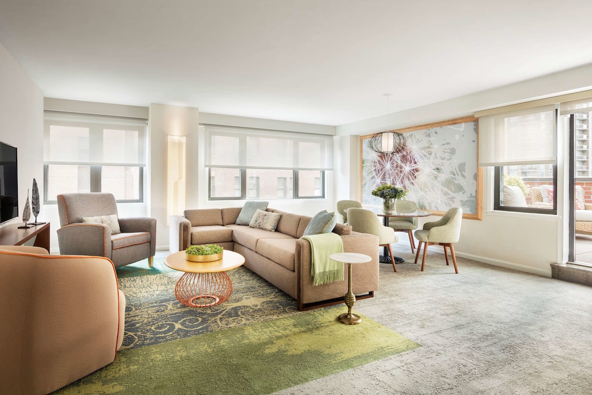 Una sala de estar moderna con un sofá modular, sillones, una mesa de centro y un televisor.