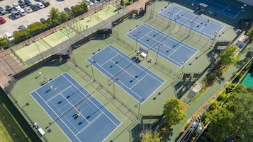 Vue aérienne d’un complexe sportif polyvalent comprenant des courts de tennis, un parking et une piscine.