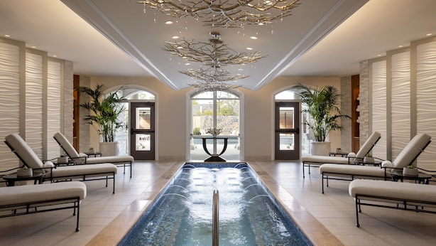 Uma área interna de piscina moderna com espreguiçadeiras e teto decorativo.