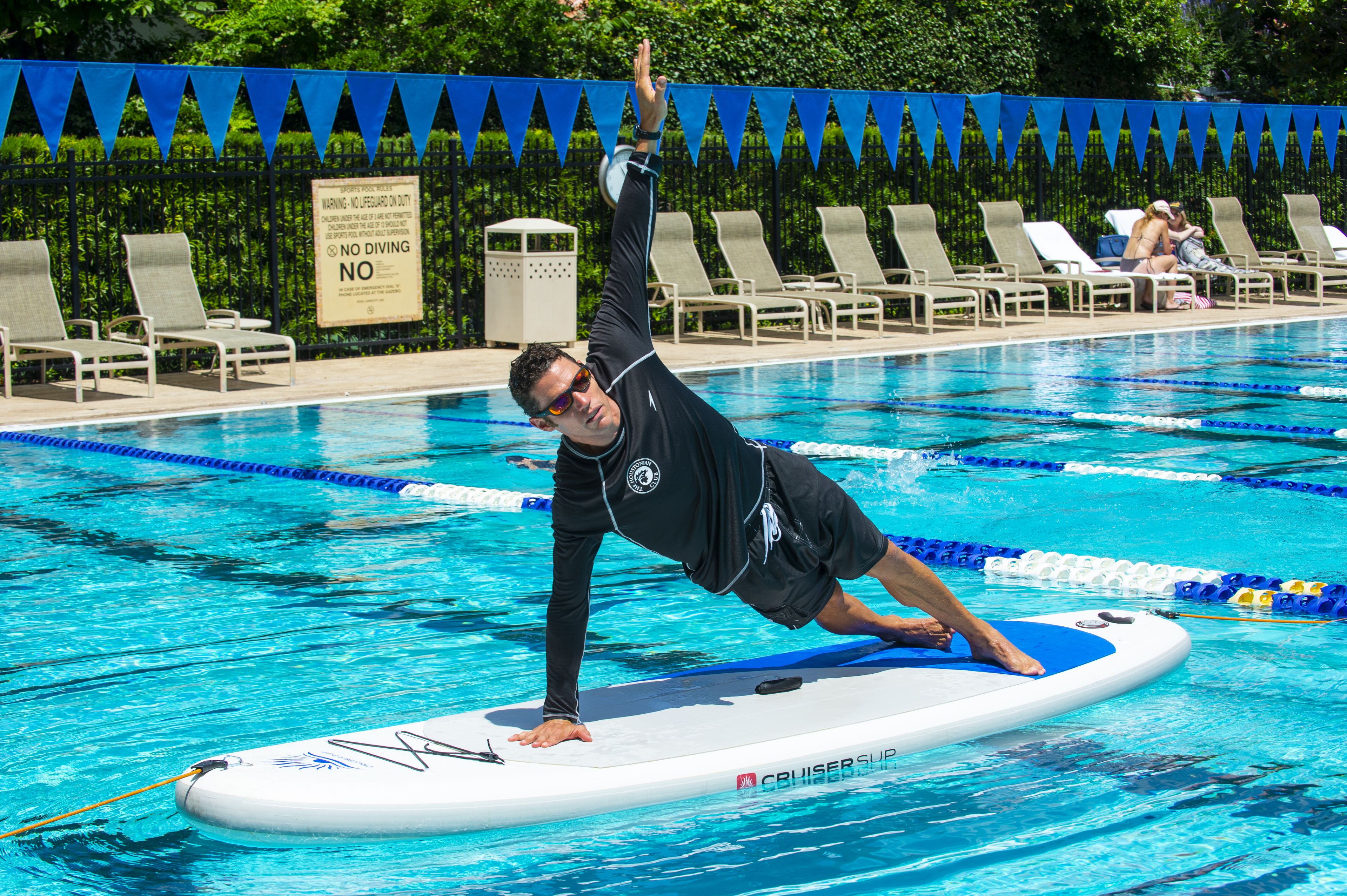 Una piscina con separadores de carriles, un puesto de socorrista y sillas de descanso a lo largo de la piscina.