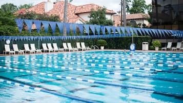Una piscina con separadores de carril, sillas de descanso y un reloj.