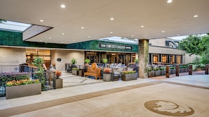 Exterior do Hotel Houstonian com design moderno, incluindo uma parede verde, área de estar externa e um grande logotipo no chão.