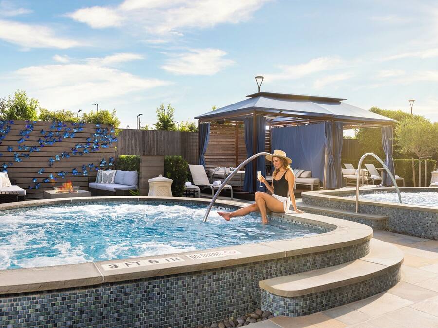 Una piscina con bordo piastrellato, sdraio, un gazebo e un recinto di legno decorato con farfalle.