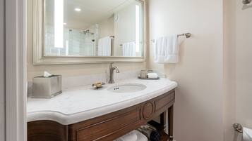 A bathroom with a marble sink, a large mirror, a towel rack, and a towel dispenser.