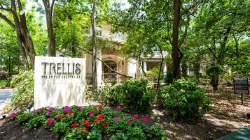 A sign for 'Trellis' spa at the Monticello, surrounded by lush greenery and a well-maintained garden.