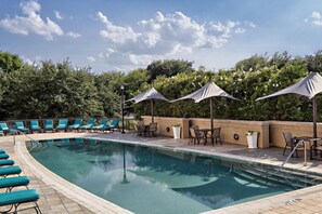 A swimming pool with lounge chairs and umbrellas, surrounded by a brick wall and greenery. - Hyatt Regency DFW International Airport - Adjacent to Terminal C (Dallas)