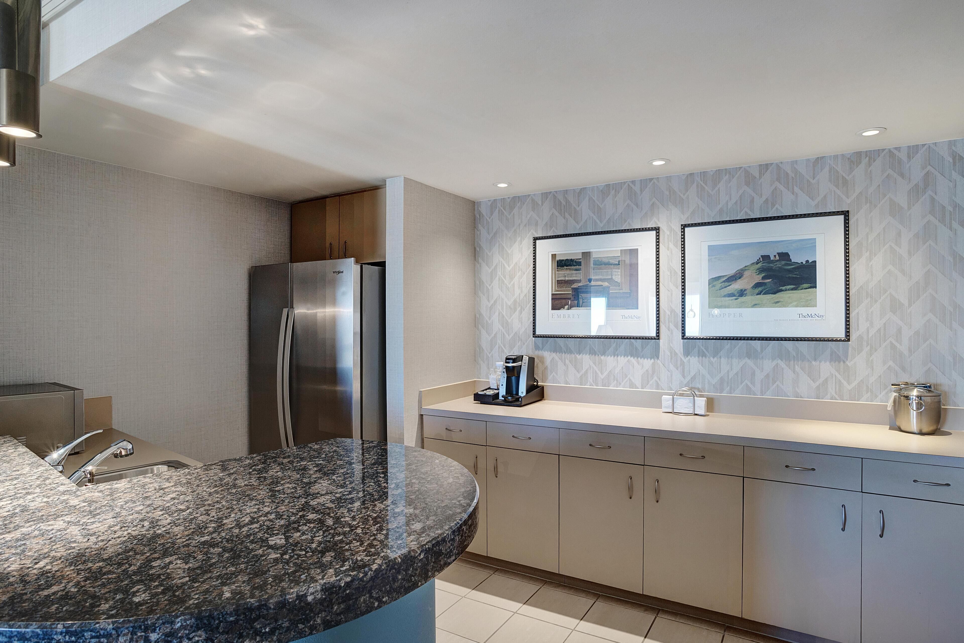 A modern kitchen with granite countertops, stainless steel appliances, and a herringbone-patterned backsplash.