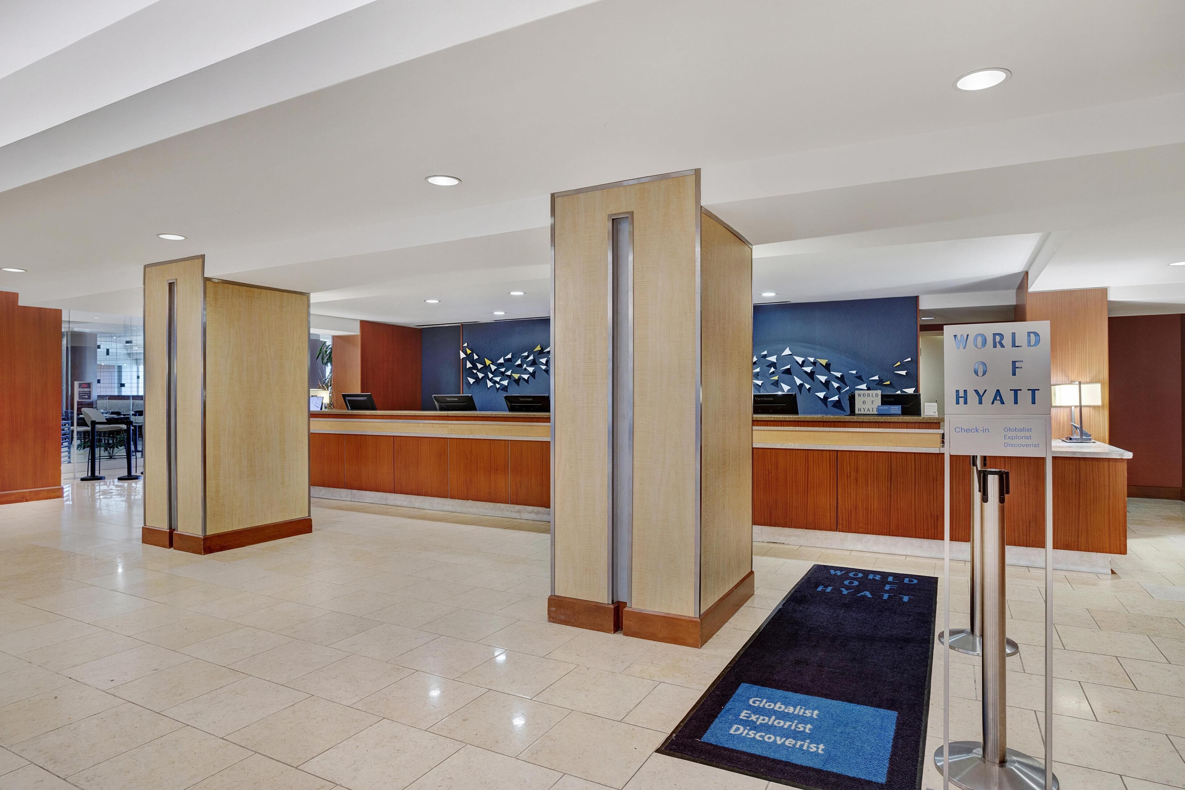 En hotellobby med en incheckningsdisk, en receptionsdisk och en skylt som visar hotellets namn.