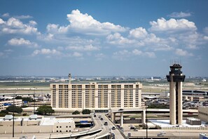 A large building with multiple floors, a control tower, and a highway with vehicles. - Hyatt Regency DFW International Airport - Adjacent to Terminal C (Dallas)