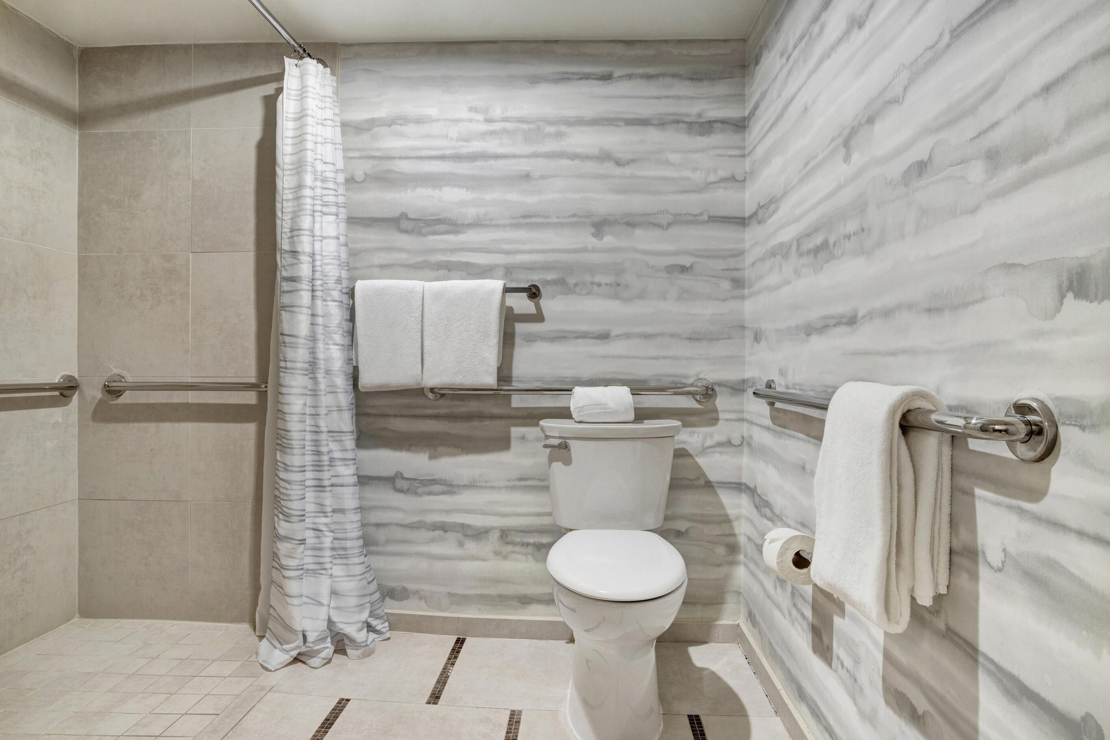 A bathroom with a shower, toilet, and towel rack.