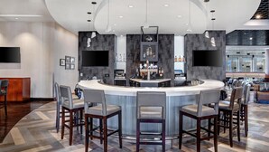 A modern bar area with a curved counter, bar stools, and a television screen. - Hyatt Regency DFW International Airport - Adjacent to Terminal C (Dallas)