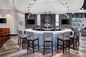A modern bar area with a curved counter, bar stools, and a television screen. - Hyatt Regency DFW International Airport - Adjacent to Terminal C (Dallas)