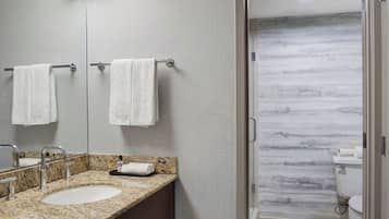 A modern bathroom with two sinks, a mirror, and a toilet visible through an open door.