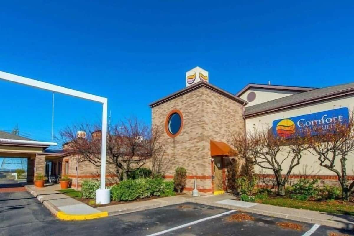 A Comfort Inn with a stone facade, a parking lot, and a clear blue sky.