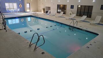 Swim laps in the clear, rectangular indoor pool with multiple lanes and lounge chairs for relaxation.