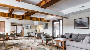 A spacious living area with a high ceiling, wooden beams, a patterned carpet, and a sofa. - Quality Inn Pagosa Springs (Pagosa Springs)