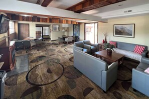 A spacious room with a large sofa, a dining table, and a television. - Quality Inn Pagosa Springs (Pagosa Springs)