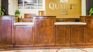A reception area with wooden reception desks, a wall-mounted sign reading "Quality Inn by Choice Hotels," and three framed pictures on the wall. - Quality Inn Pagosa Springs (Pagosa Springs)