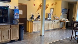 A restaurant with a counter, a refrigerator, and a coffee machine. There is a clock on the wall and a bicycle hanging on the ceiling. - Quality Inn Pagosa Springs (Pagosa Springs)