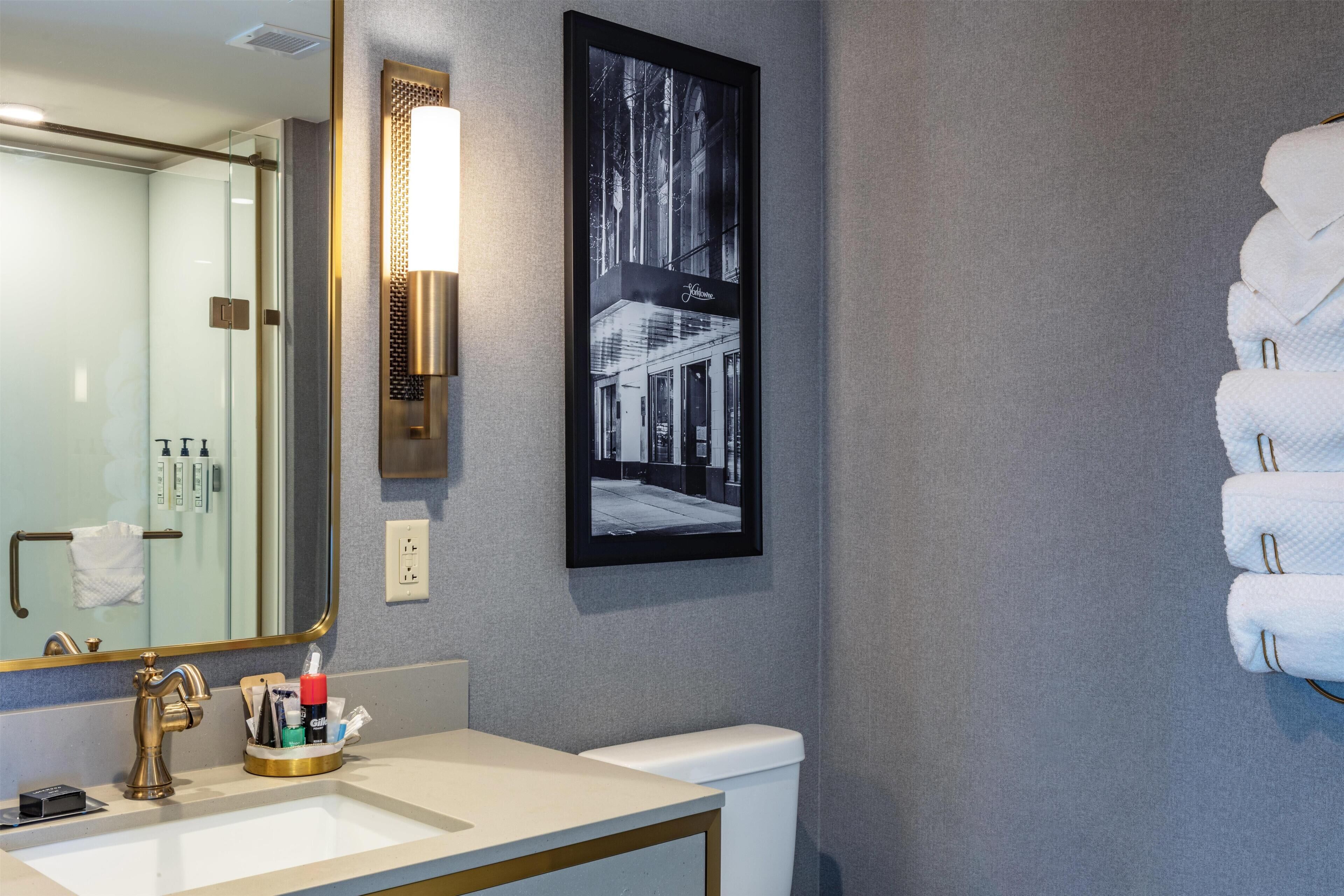 Un baño con un espejo grande, un lavabo, un inodoro y un cuadro en la pared.