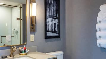 Un baño con un espejo grande, un lavabo, un inodoro y un cuadro en la pared.