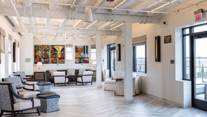 Un amplio salón con mobiliario moderno, suelo de espiga y ventanas grandes.