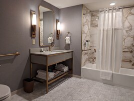 A modern bathroom with a marble shower, a vanity with a gold frame, and a toilet.